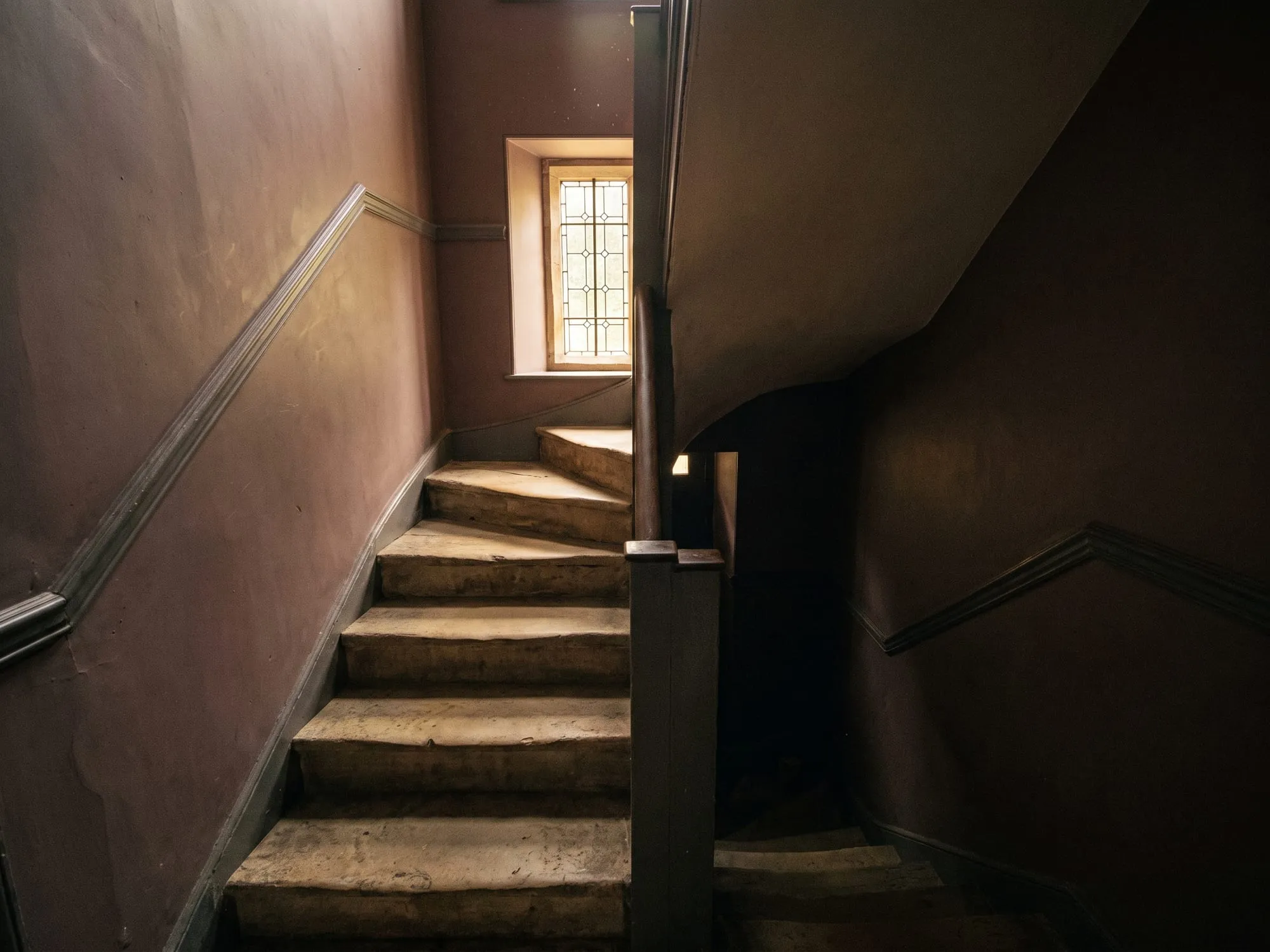 The stone stair up to the clinic, lit from a window above